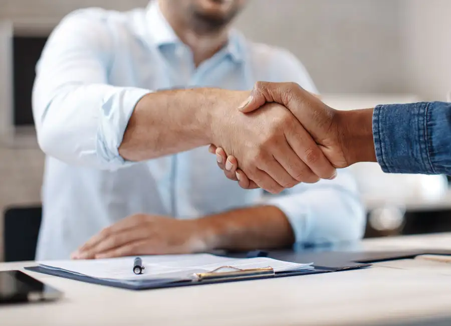 Close-up of two people shaking hands upon signing paperwork